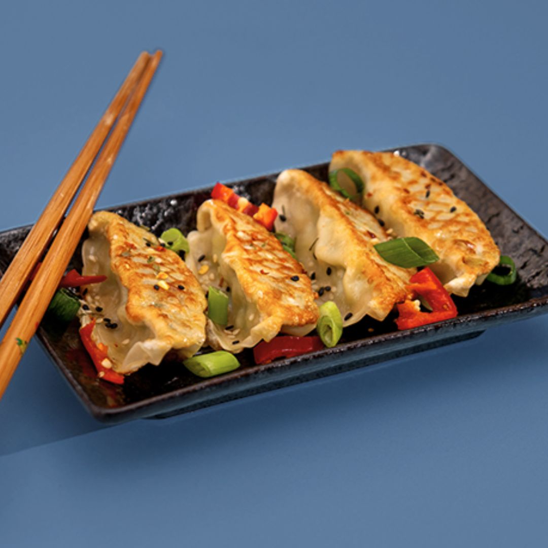 Pan-fried gyoza dumplings served with chopsticks and garnishes from the Ding Dong Dim Sum range.